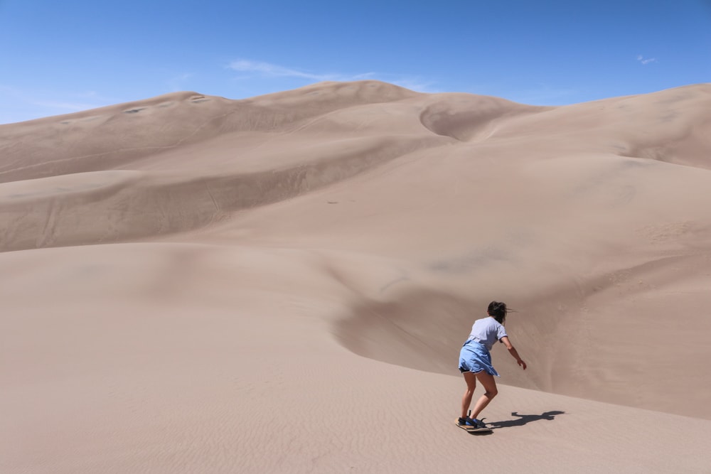 Sand boarding in Great Sand Dunes National Park, an amazing less-crowded national park to explore in summer
