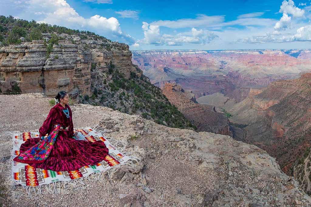 Native American women sitting on the rim of the Grand Canyon - Image Credit NPS M. Quinn