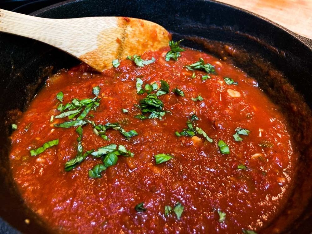 Marinara sauce with basil in cast-iron pot with wooden spoon
