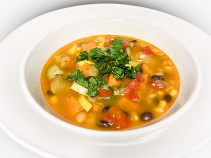 Three sisters soup recipe with corn, beans and squash in white bowl
