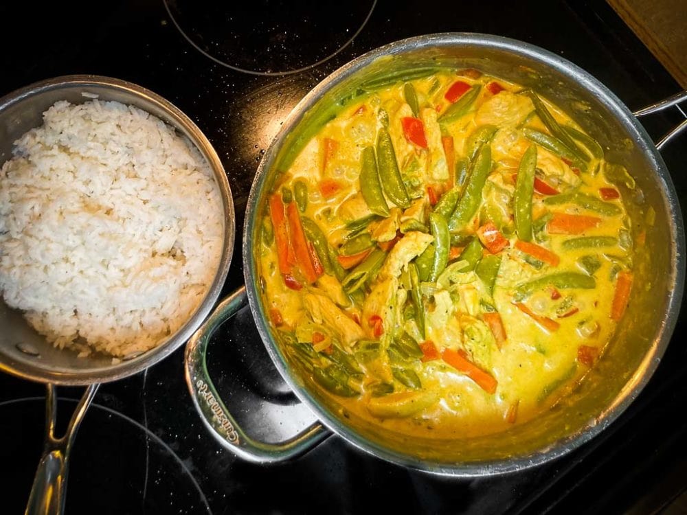 Creamy curried chicken on stove with white rice