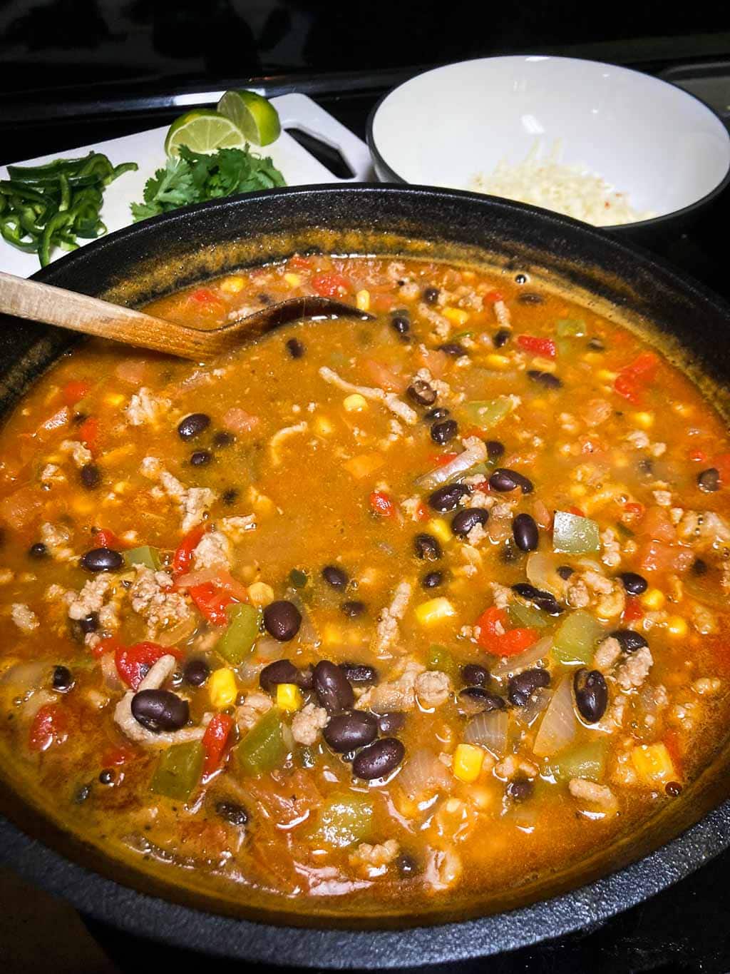 Ground turkey taco soup in cast-iron pot with toppings