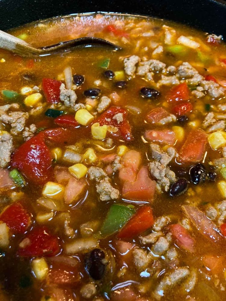 Ground turkey taco soup in cast-iron pot with wooden spoon