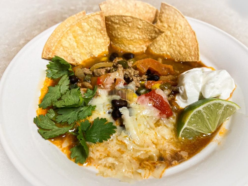 Ground turkey taco soup in serving bowl with toppings and tortilla chips