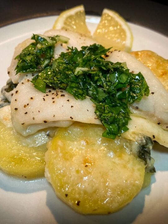 Halibut and scalloped potatoes with parsley gremolata on top