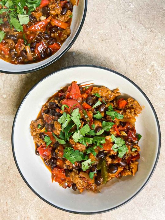 Chorizo, black beans and roasted bell pepper skillet dish in bowls on counter