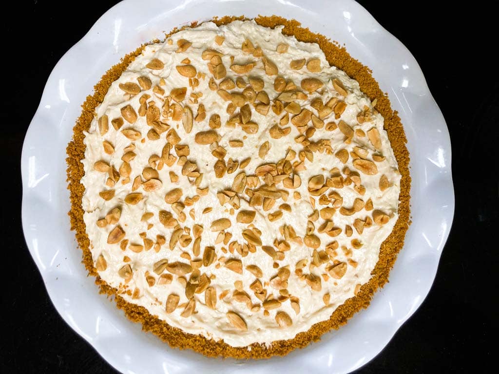 Peanut butter cream pie with chopped peanuts in pie dish