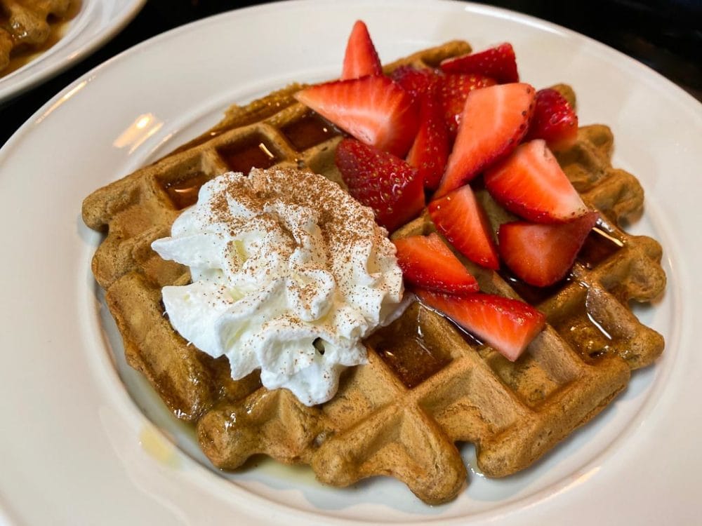 Spiced pumpkin waffle with maple syrup, strawberries and whipped cream