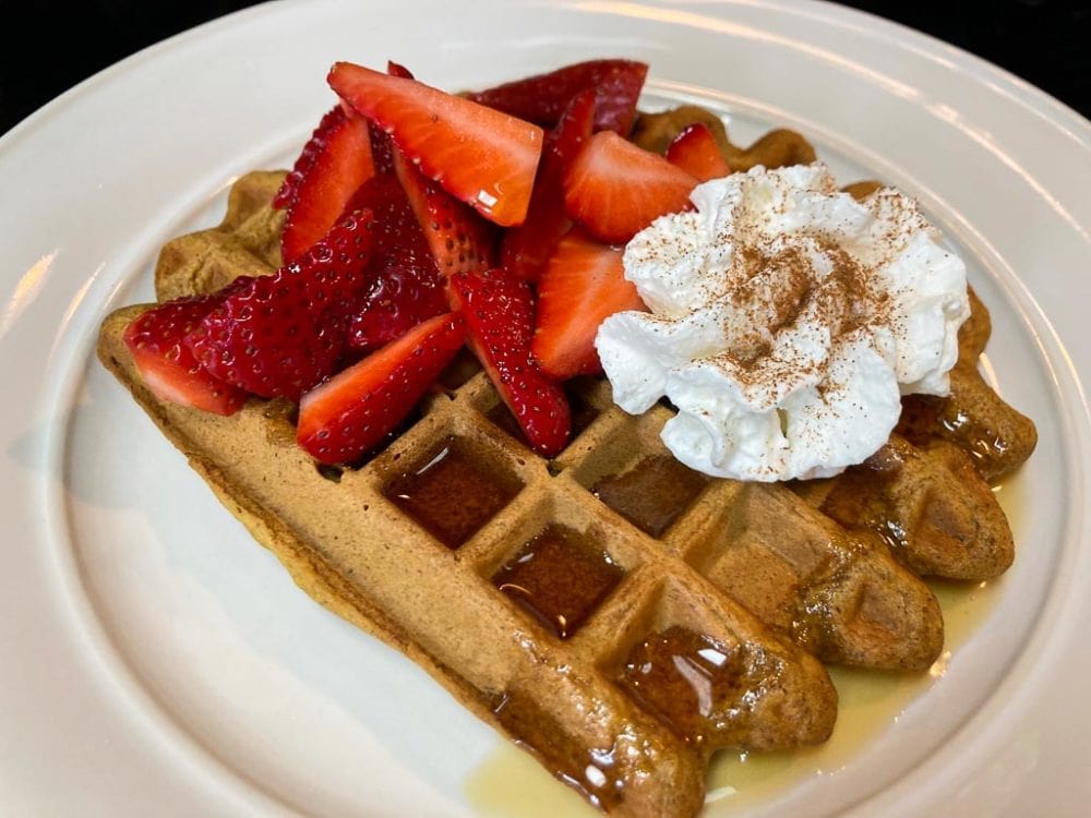 Spiced pumpkin waffles recipe with strawberries, whipped cream and maple syrup