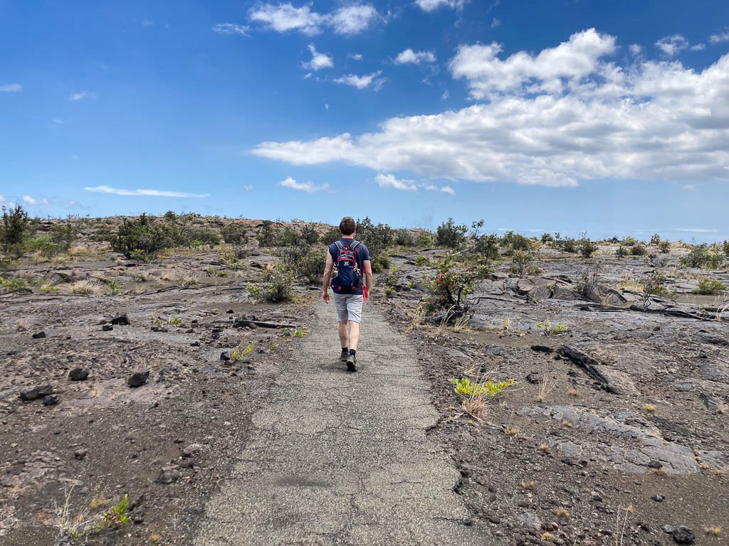 Footprints and Maunaiki Trail hiker in Kaʻū Desert, Hawai‘i Volcanoes National Park, Hawaii