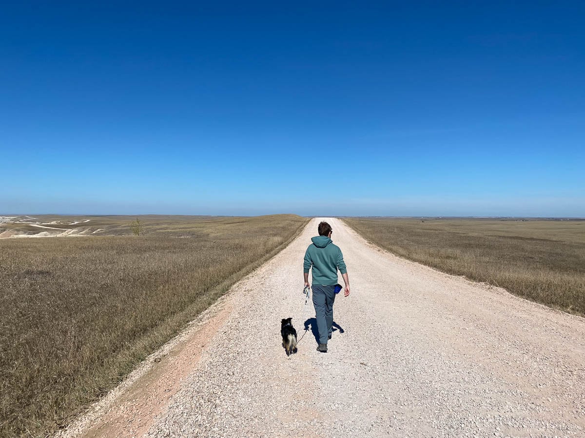 Sage Creek Rim Road hiker with small dog, Badlands National Park, South Dakota