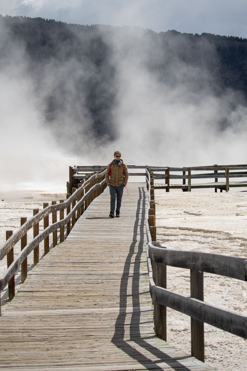 Visitor walking on the Lower Terraces boardwalk at Mammoth Hot Springs, one of the greatest hikes in Yellowstone National Park to do in spring