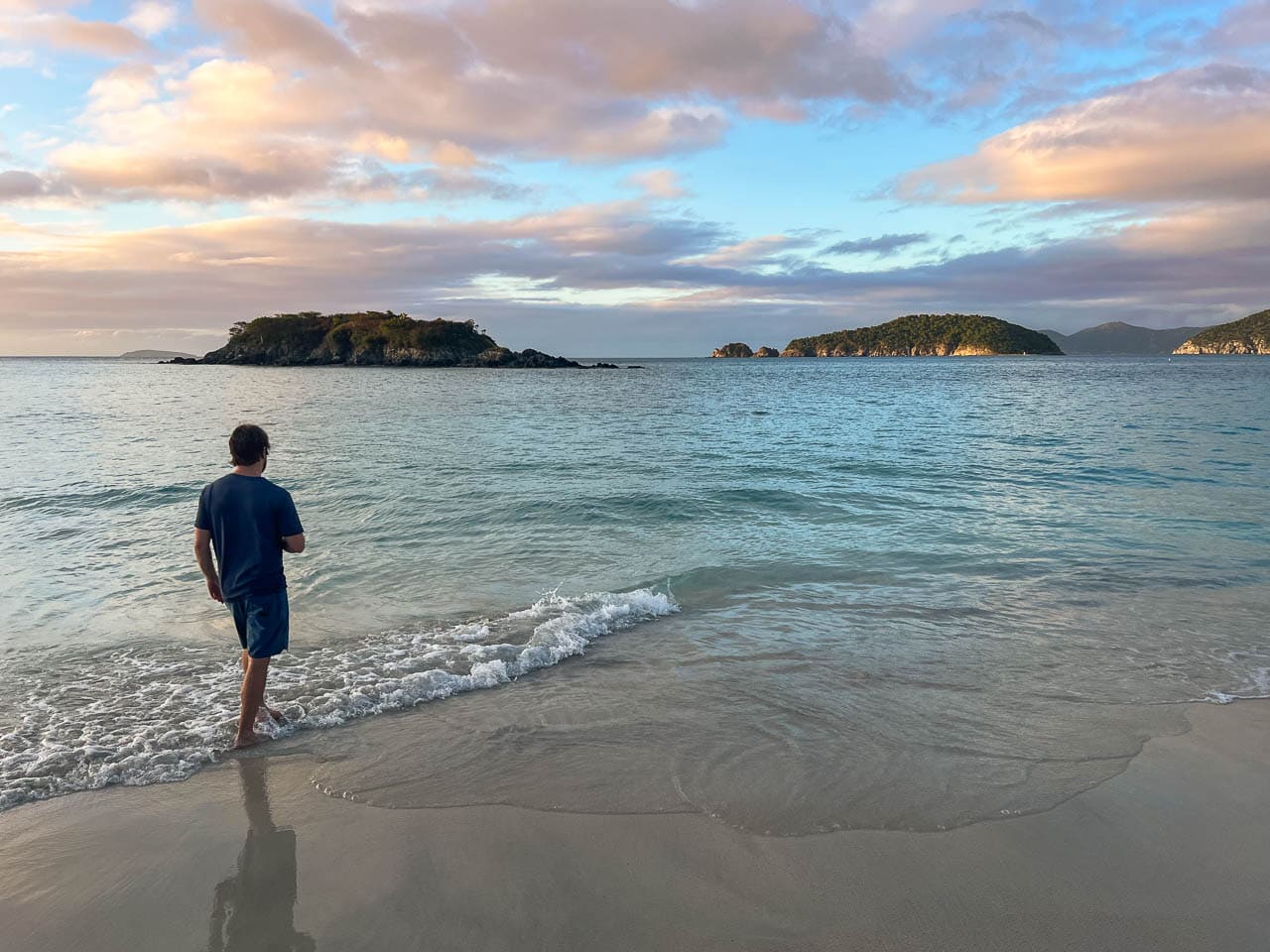 Visitor walking in the water on Cinnamon Bay Beach at sunset, Virgin Islands National Park
