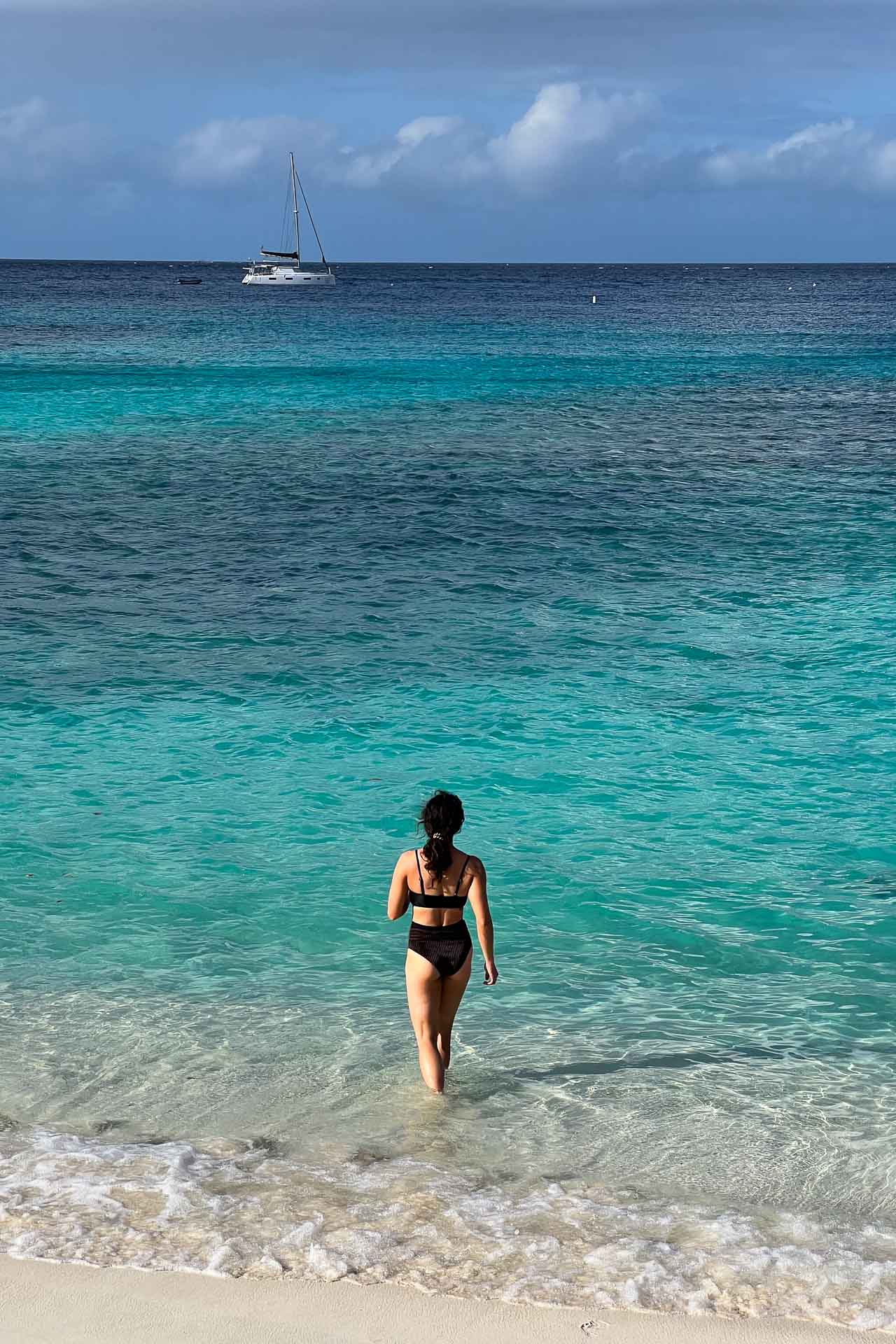 Visitor walking in the turquoise water Hawksnest Bay Beach in Virgin Islands National Park
